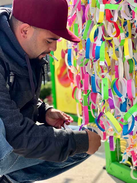 Visitors adding ribbons to Broken Wings installation