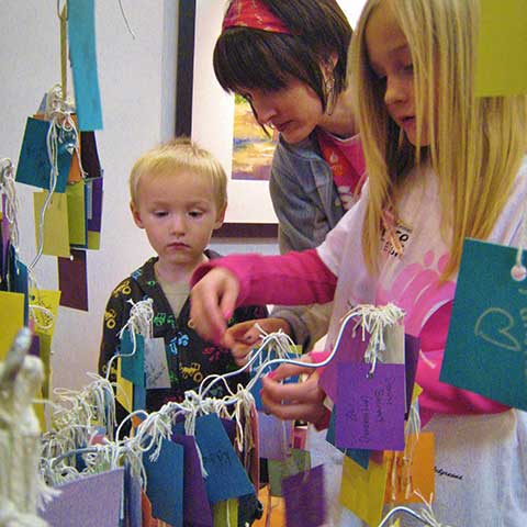 Mother with children adding Hope Card to Healing Tree