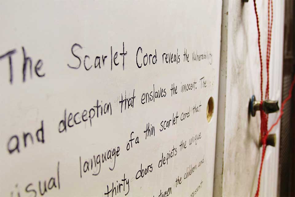 Weathered doors tied with red rope used in The Scarlet Cord installation
